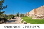 Defensive wall of the ancient holy Jerusalem timelapse hyperlapse, lit by the bright sun. Wonderful green lawn near walkway and blue sky