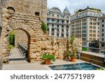 defensive walls of Barcelona, Spain, and the base of Chapel of Santa Agata in the background, in contrast to the buildings on Via Laietana on the right, built in the late 19th and early 20th centuries