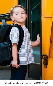 Defiant Young Boy In Front Of Yellow School Bus Waiting To Board On First Day Back To School.