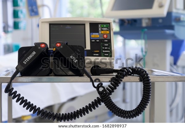 Defibrillator,  on background medical ventilator in\
ICU in hospital, a place where can be treated patients with\
pneumonia caused by coronavirus covid\
19.