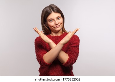 Definitely no, prohibited access! Portrait of girl in shaggy sweater crossing hands, showing x sign, stop gesture, warning of end finish, forbidden way. indoor studio shot isolated on gray background