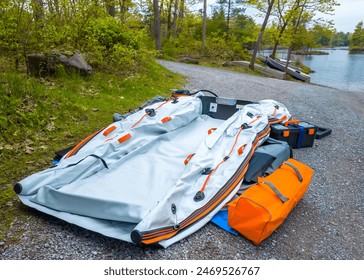 Deflated Boat catamaran pvc dinghy or rowboat pontoon with electric trolling motor and lithium battery fishing preparation. Vacation and leisure hobby. Inflatable boat. - Powered by Shutterstock