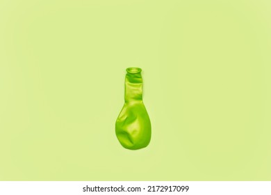 A Deflated Green Balloon On A Green Background With Copy Space