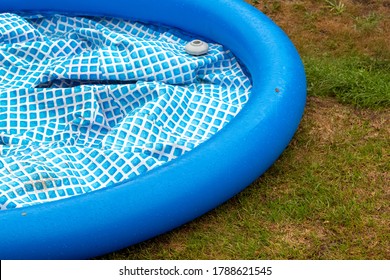 A Deflated Inflatable Pool On The Backyard Lawn.