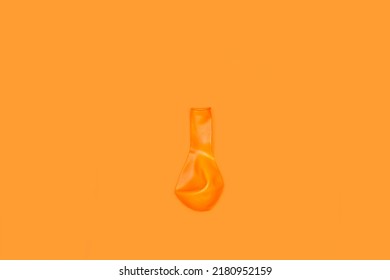 A Deflated Orange Pink Balloon On An Orange Background With Copy Space