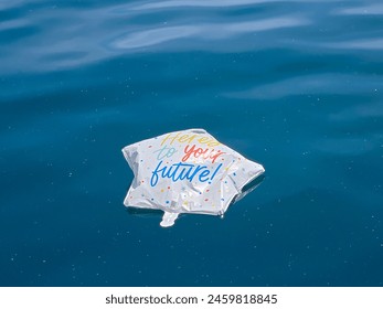 Deflated star-shaped graduation balloon floating on calm blue Lake Michigan water - Powered by Shutterstock