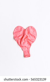 Deflated Wrinkled Pink Heart Shaped Balloon Laying Flat On White Background