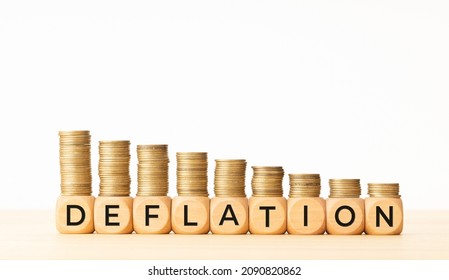 Deflation concept. Text on wooden blocks and stacked coins. Copy space