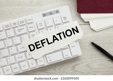 Deflation concept. torn white paper on a white keyboard. text in black