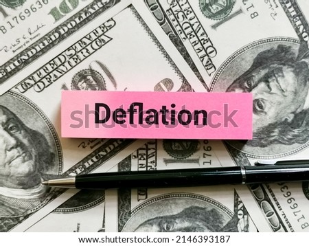 Deflation written on sticky note with a pen and fake money.