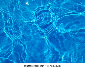 Defocus blurred blue water in swimming pool rippled water detail background. Water surface in the sea, ocean background. Water is an inorganic, transparent, tasteless, odorless, and nearly colorless.