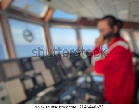 defocus and blurred image of a long-haired male sailor wearing a red coverall was piloting the ship, maneuvering the ship to dock. a seafarer under controlling vessel due to maneuver for alongside 