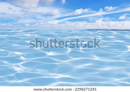 Defocus blurred transparent blue sea and sky. water surface texture with splashes and bubbles. Trendy abstract nature background. Water waves in sunlight with copy space. Blue water shine