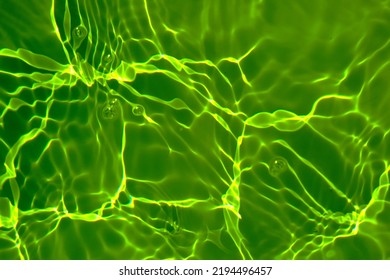 Defocus blurred transparent green colored clear calm water surface texture with splash, bubble. Shining green water ripple background. Surface of water in swimming pool. Tropical green water textures.