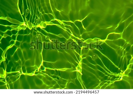 Defocus blurred transparent green colored clear calm water surface texture with splash, bubble. Shining green water ripple background. Surface of water in swimming pool. Tropical green water textures.