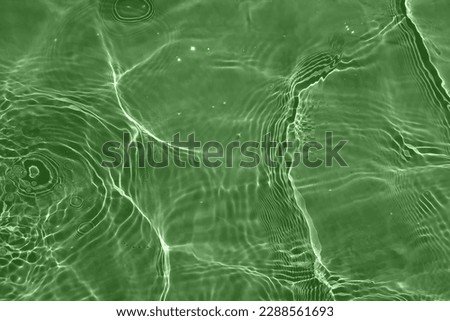 Defocus blurred transparent green colored clear calm water surface texture with splashes and bubbles. Trendy abstract nature background. Water waves in sunlight with copy space. Green water shine