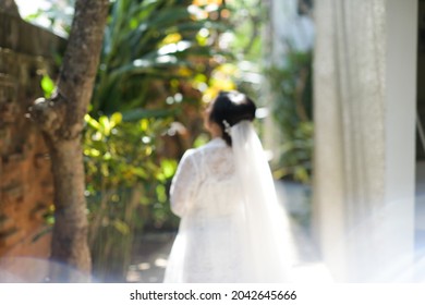 Defocus, a bride is looking at the trees around the hotel.