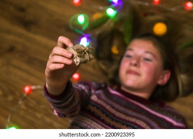 Defocus Christmas Girl Holding Gift On The Floor. Top Above High Angle View Photo Of Happy Young Woman Hold Hands Face Xmas Floor Gifts Indoors Inside House Home. Out Of Focus.