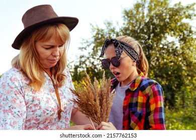 Defocus mother and daughter. Splinter on finger. Teen or preteen girl walking on nature background with young woman. Holding bunch of pampas grass. Green meadow, field. Family. Autumn. Out of focus.