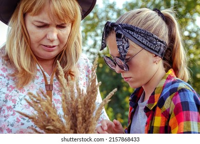 Defocus mother and daughter. Splinter on finger. Teen or preteen girl walking on nature background with young woman. Holding bunch of pampas grass. Closeup. Autumn. Out of focus.