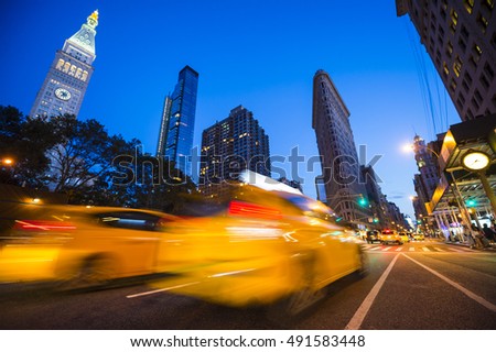 Defocus motion blur view of yellow taxis driving through the city streets at dusk in New York City, USA. Slow shutter speed to enhance motion blur effect.