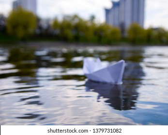 Defocus White Paper Boat In Blue Water. Symbolizes Uncertainty And Unpredictability Of The Future. You Never Know What To Expect In Life. Concept Of Blurry Perspective.