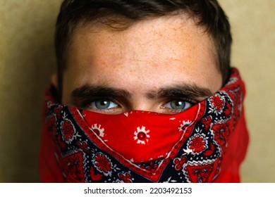 Defocus Young Man In Red Bandana. Closeup Blue Dark Eyes. Man With His Face Hidden Behind A Bandanna Stares Balefully At The Camera. Out Of Focus.