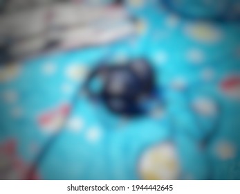 Defocused Abstract Background Of Black Headphones Lying On The Blue Bed Cover