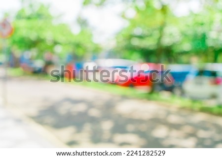 Defocused abstract background of a car park area surrounded by trees. Blurred out park area background