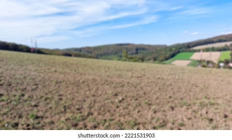 Defocused abstract background of farmfield and blue sky with clouds. Plain landscape background.