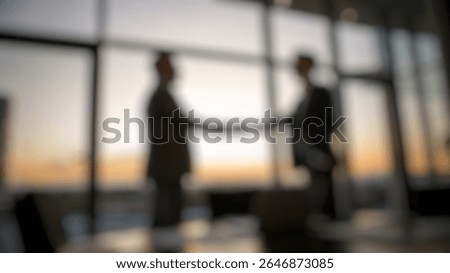 Defocused abstract background of sunset handshake in glass-wall office, deal made between two partners.