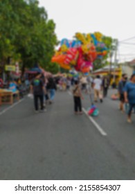 Defocused Abstract Background Of A Toy Seller In A Crowded City Park.