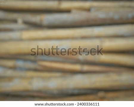 Defocused abstract background of used bamboo piles in the construction of a house with a cast splatter of cement attached.