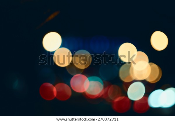 Defocused abstract lights\
street background. Festive Lights Bokeh Street Lights. Abstract\
background spherical bokeh of car lights in the hight. Instagram\
color style.