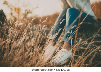 Defocused Abstract Loneliness Concept. Cropped Feet Of Lonely Young Woman Sitting On Stone. Solitude