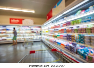 The Defocused Blur Of Female Drink Milk Food Buying Cart Shopping Put On A Shelf At The Drink In The Supermarket.