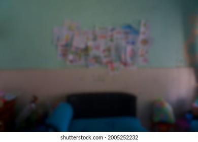 De-focused Blur Of Messy Living Room With Lots Of Paper Drew, Colored, And Unorganized Taped By Kids To The Wall.