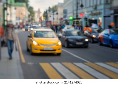 Defocused Blured View Of City Street Scene, Downtownm, Urban Traffic, Yellow Car Before The Pedestrian Crossing Next To The Sidewalk Abstract Urban Background.