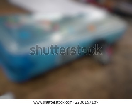 Defocused or blurred abstract background of school utensils such as a blue pencilcase and a black rubber eraser put on the wooden table