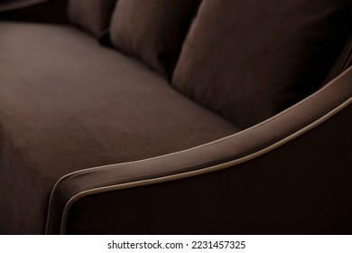 Defocused blurred background of a brown sofa with cushions and beige edging on the elbow of soft fleecy velor. Upholstered furniture close-up in deep shadows with copy space. - Powered by Shutterstock