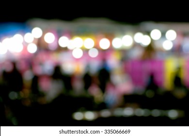 Defocused And Blurred Photo Of People In The Night Amusement Park, Used For Background Or Backdrop Concept.