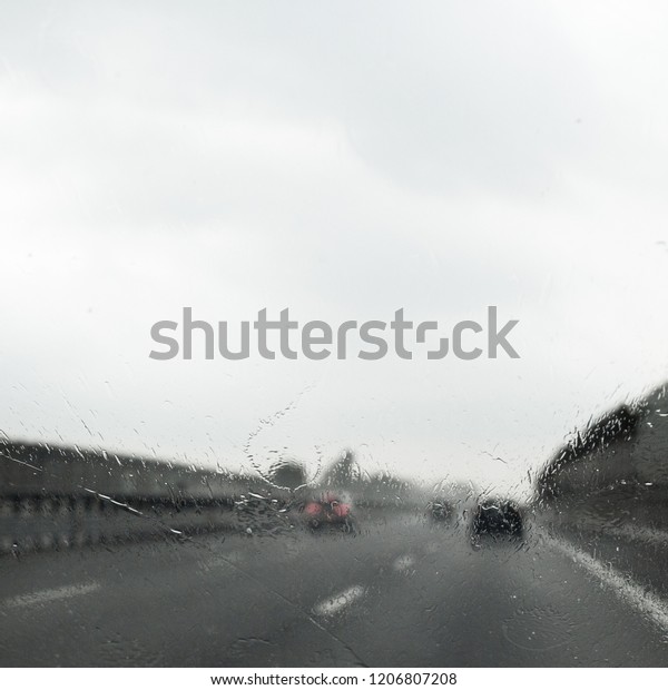 defocused and blurred point of\
view inside the car, traveling on the highway, bad weather, raining\
day
