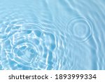 De-focused blurred transparent blue colored clear calm water surface texture with splashes and bubbles. Trendy abstract nature background. Water waves in sunlight with copy space.