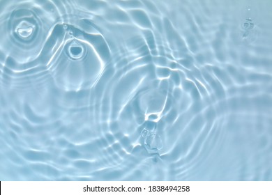 De-focused blurred transparent blue colored clear calm water surface texture with splashes and bubbles. Trendy abstract nature background. Water waves in sunlight with copy space.