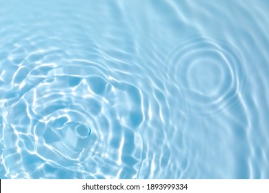De-focused blurred transparent blue colored clear calm water surface texture with splashes and bubbles. Trendy abstract nature background. Water waves in sunlight with copy space. - Shutterstock ID 1893999334