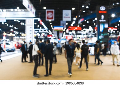 Defocused Blurry Crowd Anonymous People Walking At  Exhibition Business Trade Fair Show At Convention Display Event Or Conference Hall. Light Bokeh Background.