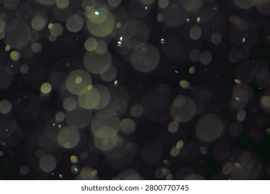 Defocused bokeh lights of different sizes and colors on a dark background.