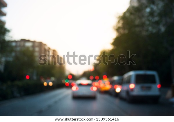 Defocused cars in the traffic and stop lights\
are on in the\
evening.