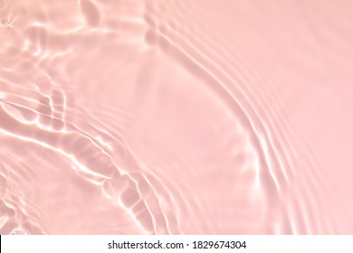 De-focused. Closeup Of Pink Transparent Clear Calm Water Surface Texture With Splashes And Bubbles. Trendy Abstract Summer Nature Background. Coral Colored Waves In Sunlight.