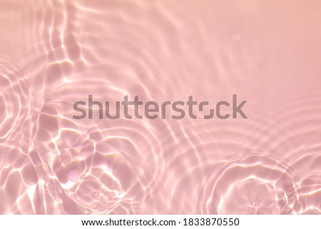 de-focused. Closeup of pink transparent clear calm water surface texture with splashes and bubbles. Trendy abstract summer nature background. Coral colored waves in sunlight.